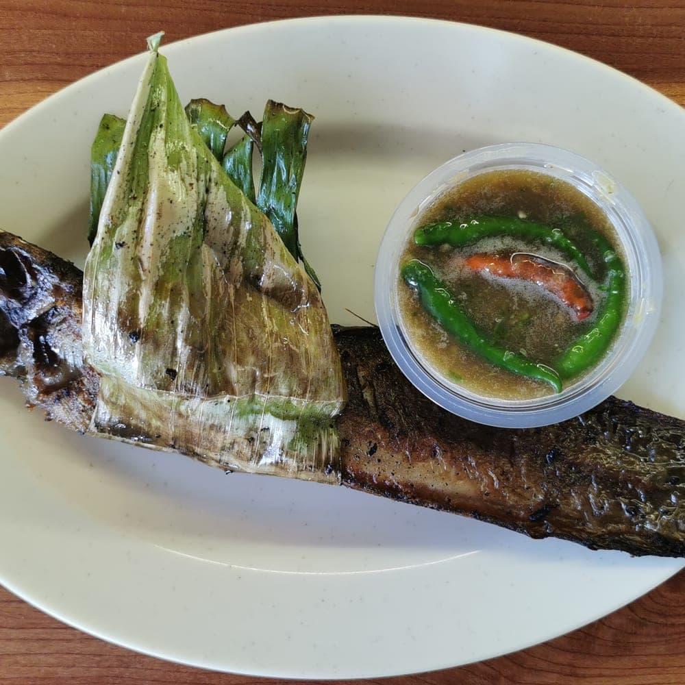 Ikan keli bakar berbalut daun pisang dihidang dengan kuah air asam